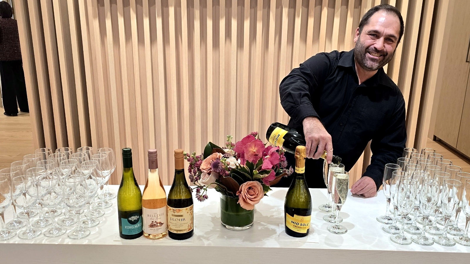 Bartender pouring champagne at an event bar.